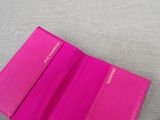 a pink passport case sitting on top of a gray surface