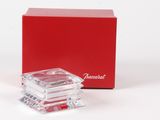 une petite boîte rouge contenant un objet en verre transparent
