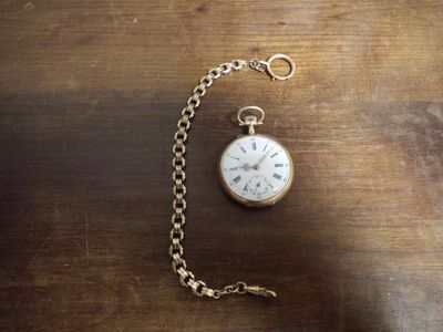 une montre de poche attachée à une chaîne, posée sur une table en bois