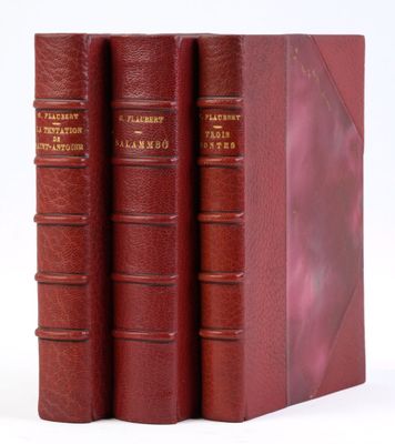 trois livres rouges superposés sur une surface blanche
