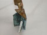 bronze sculpture of a bird perched on a rock with a knife in it ' s beak