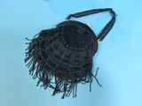 black beaded purse with fringes on a blue surface