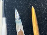 two pens and a pencil sitting on a black surface