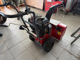 a red snow blower sitting on the floor in a garage