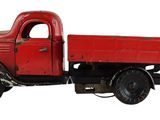 un petit camion rouge posé sur une surface blanche