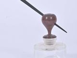 a small glass jar with a wooden handle on it