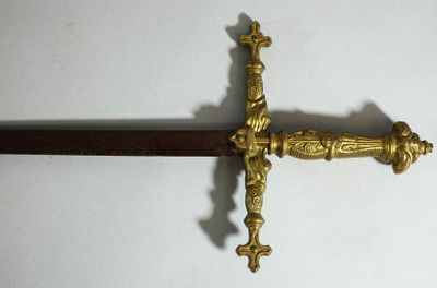 une épée dorée ornée d'une croix, sur un fond blanc