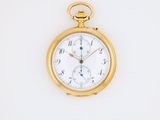 a close up of a gold pocket watch on a white surface
