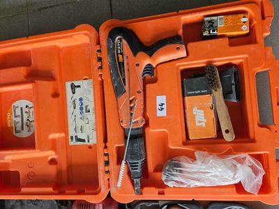 une mallette à outils orange, contenant des outils, posée par terre