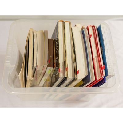un bac en plastique rempli de nombreux livres posé sur une table