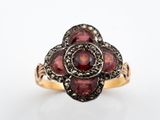 un gros plan d'une bague sertie de grenats sur fond blanc