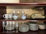many plates and glasses on a shelf in a cabinet