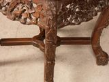 an old wooden table with a marble top on a white floor