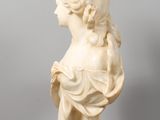 a white marble bust of a woman on a clear acrylic stand