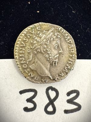une pièce d'or sur laquelle est représenté le visage d'un homme, posée sur un morceau de papier