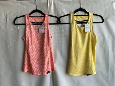 two women ' s tank tops hanging on a hanger in front of a wall