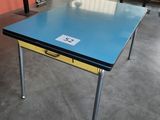 une table au plateau bleu dans une pièce aux murs orange