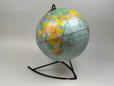 un petit globe terrestre posé sur un socle, sur fond blanc