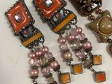 three pairs of earrings are sitting on a white surface