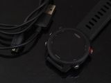 une montre connectée posée sur une table, à côté d'un chargeur