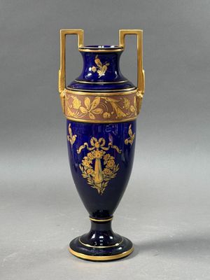 a blue vase with gold decoration on it sitting on a table