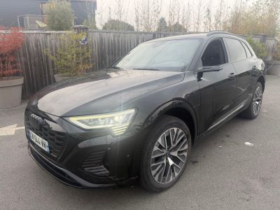 a black audi suv parked in a parking lot next to a fence
