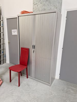 a red chair sitting in front of a metal door