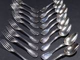 six cuillères en argent sont disposées en rangée sur une surface noire