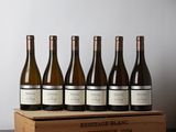 six bouteilles de vin dans une caisse en bois posée sur une table