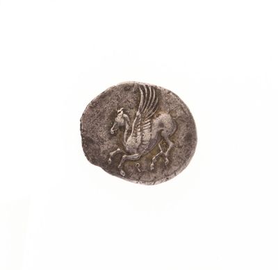 une vieille pièce de monnaie sur laquelle figure un cheval, posée sur une surface blanche