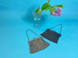 two small purses sitting on top of a table next to a vase of flowers