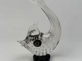 glass sculpture of a fish on a black base on a white background
