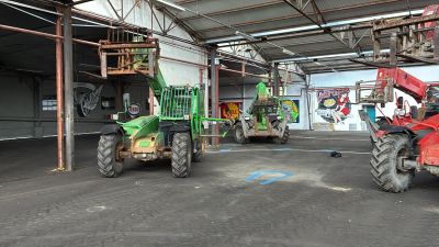 deux tracteurs garés à l'intérieur d'un bâtiment, avec un homme à l'arrière d'un tracteur