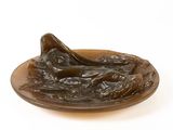 une sculpture en bronze représentant une femme allongée sur une assiette