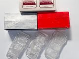 quatre petites voitures en plastique dans une boîte posée sur une surface blanche