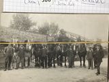 une vieille photo montrant un groupe d'hommes debout à côté d'un cheval