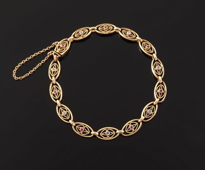 a gold bracelet with pink stones on a black background