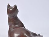 a small statue of a cat sitting on a white surface