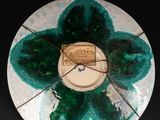 a clock that is sitting on a plate with a green flower on it