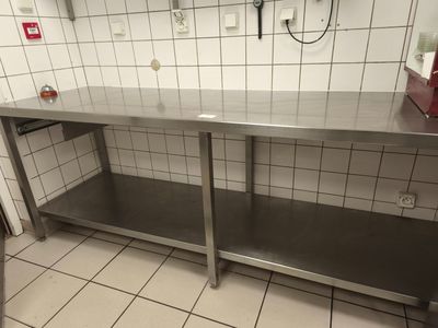une table de travail en acier inoxydable dans une cuisine aux murs carrelés