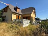 a yellow house with a brown roof and a white fence