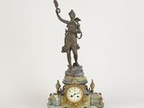 une statue d'un homme tenant une horloge au-dessus d'une table