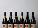 six bottles of wine lined up on a wooden table