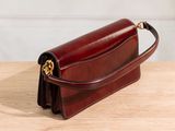 a brown leather purse sitting on top of a wooden table