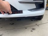 a person holding a sticker on the front of a white car