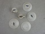 quatre tasses et soucoupes blanches ornées de motifs noirs