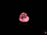un gros plan d'un diamant rose en forme de cœur sur une surface noire