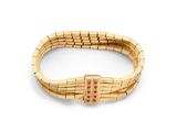 un gros plan d'un bracelet en or orné de pierres roses sur fond blanc