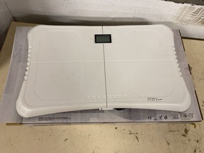 une balance électronique blanche posée sur une boîte au sol