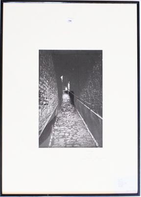 photographie en noir et blanc d'une personne marchant dans une rue étroite